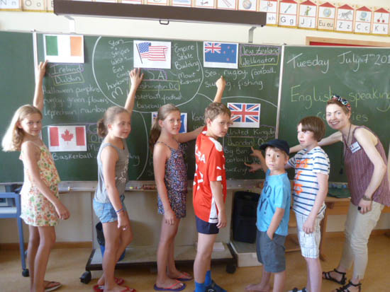 Kindergruppe in der Klasse, vor Schultafel beim Englisch lernen
